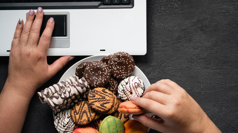 eating a plate of cookies at the computer