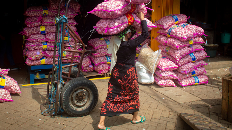 A woman carrying large bags of bulk garlic on her head