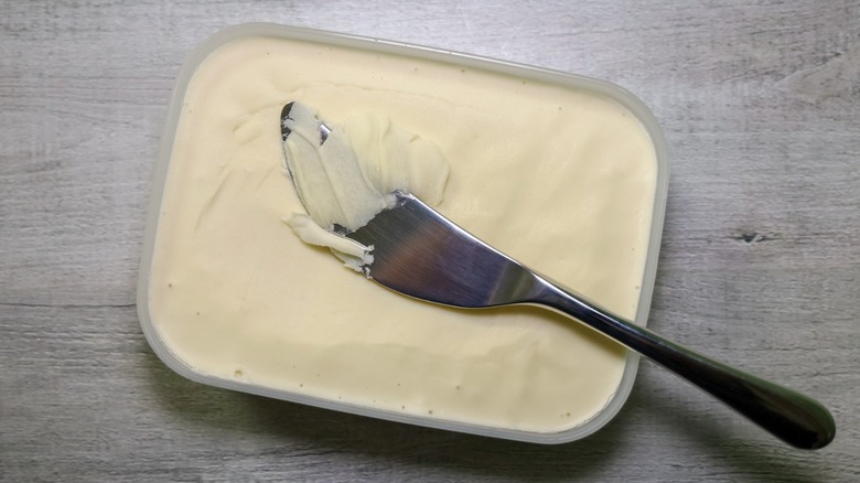 Tub of spreadable butter with a knife on top