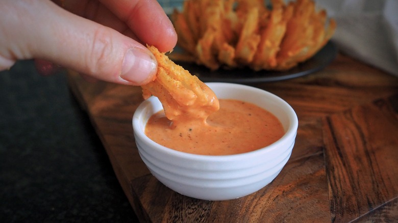 Person dipping fried onion into sauce