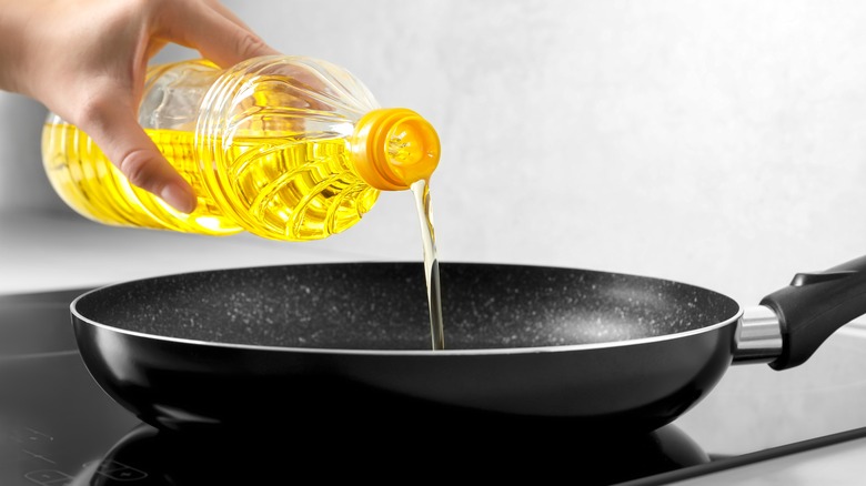 hand pouring oil into pan