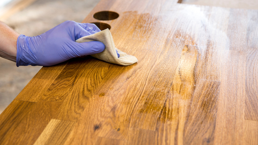 Hand rubbing a butcher block countertop with oil