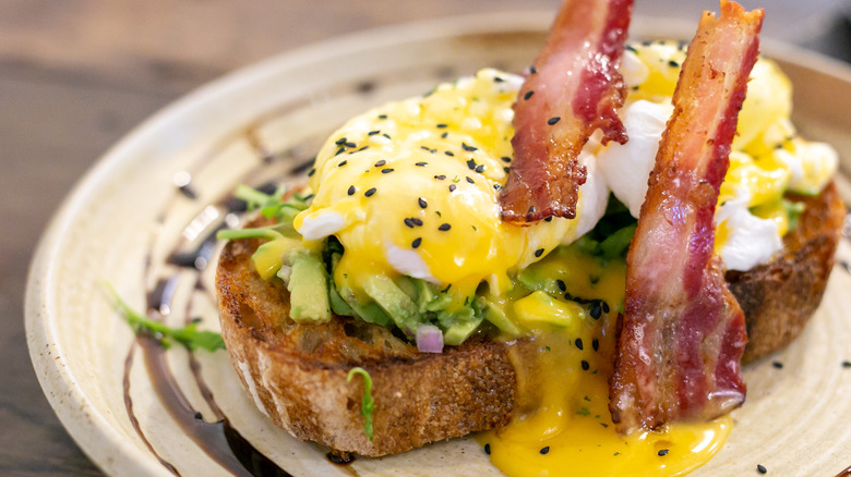 Sourdough avocado toast breakfast with eggs and bacon