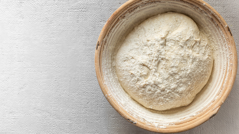 Bread dough in a wooden bowl dusted with flour