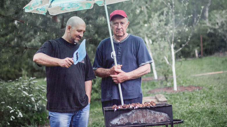 Two men grilling in the rain
