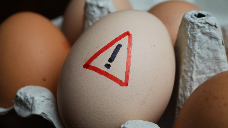 Raw egg with warning symbol