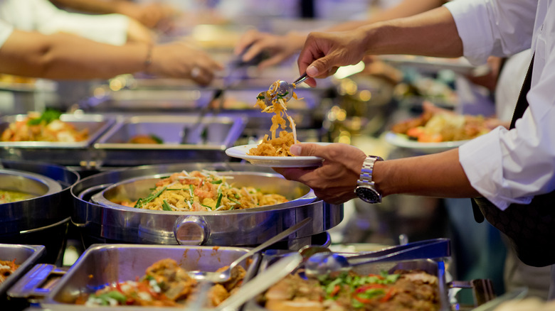 People serving food from a buffet line