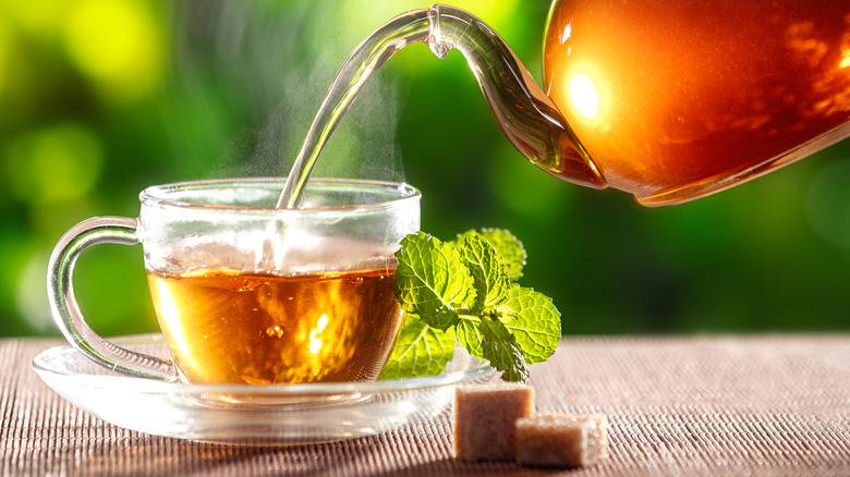 pouring tea into a glass cup