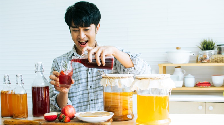 man pouring kombucha in glass