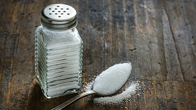 Salt shaker and spoon on wood