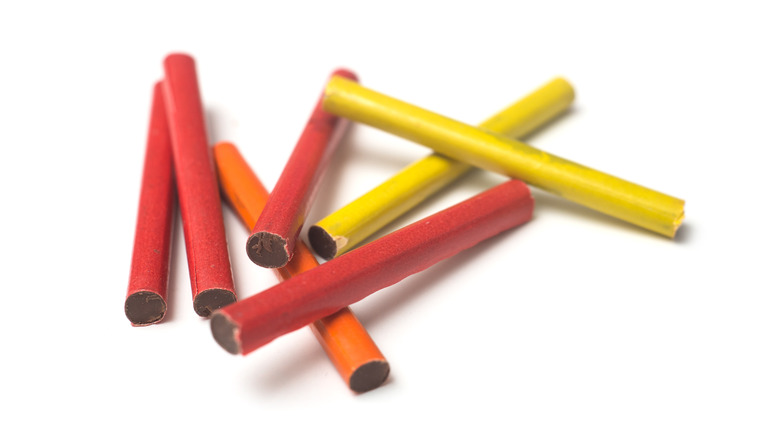 Multicolored chocolate cigarettes on white background