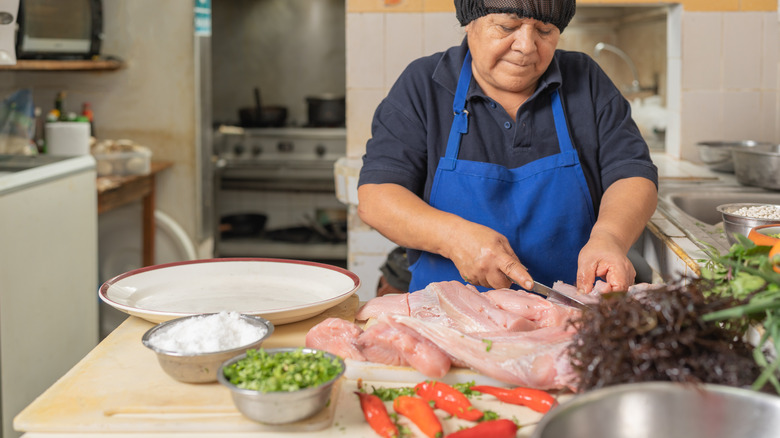 woman preparing fish with ingredients nearby