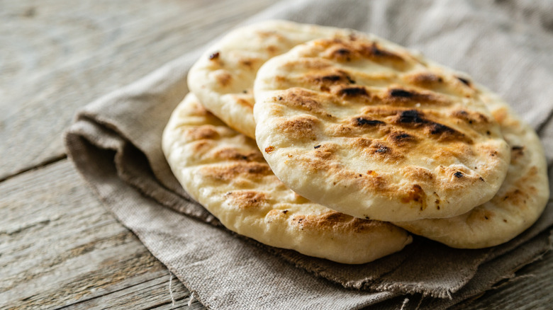 Pita bread under a cloth on a wooden table