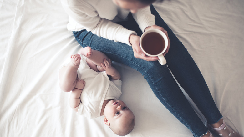 woman drinking tea besides baby