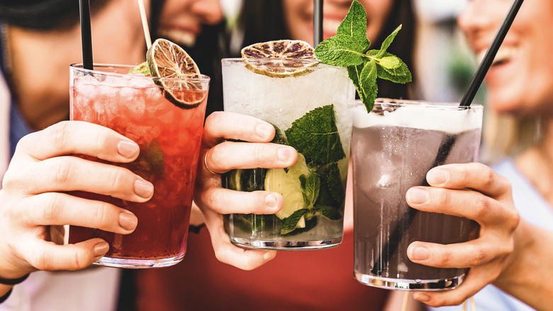 Three people toasting cocktails