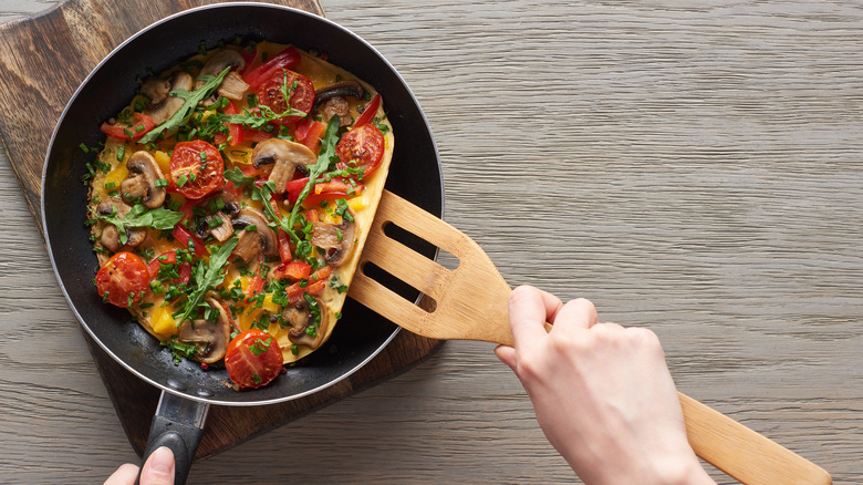 flipping omelet with wooden spatula