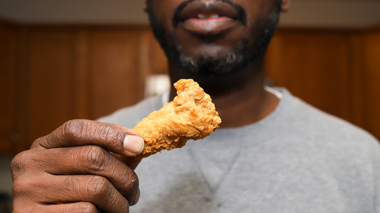 man holding a small piece of fried chicken