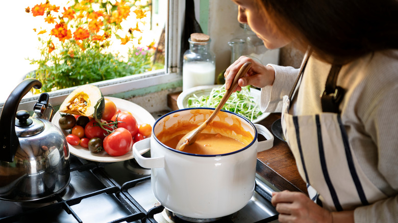 Woman stirring creamy soup on stove