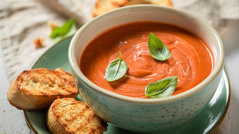 A bowl of tomato soup with bread