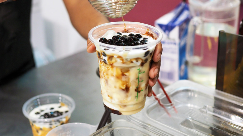 A barista putting tapioca pearls in a bubble tea