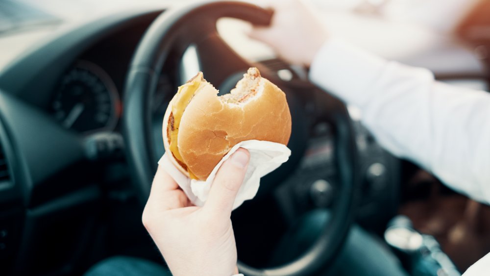 Man eating burger in a car