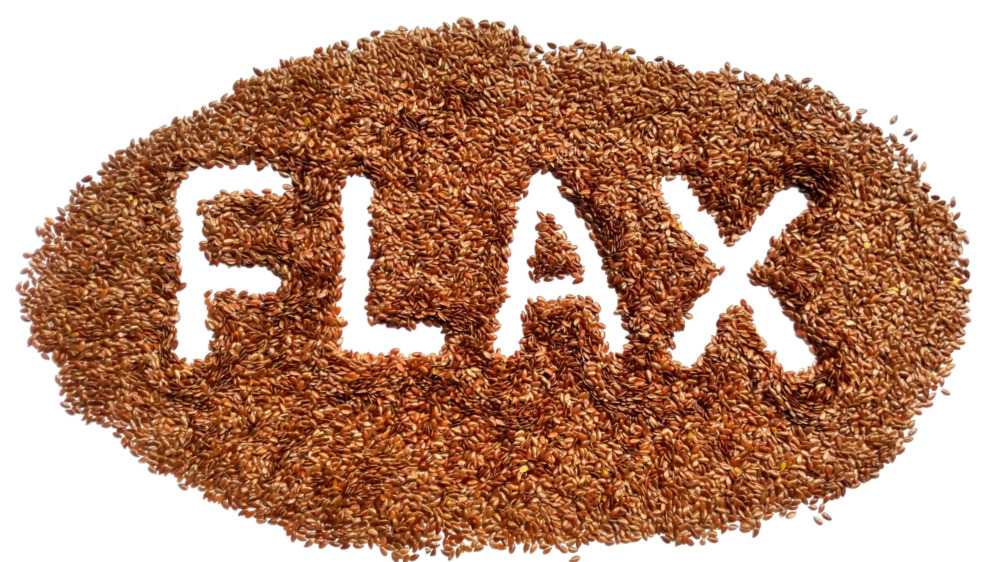 Wooden board with bowl of flaxseed and serving utensil