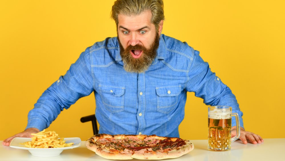 A representational photo of a guy looking at pizza with his mouth open