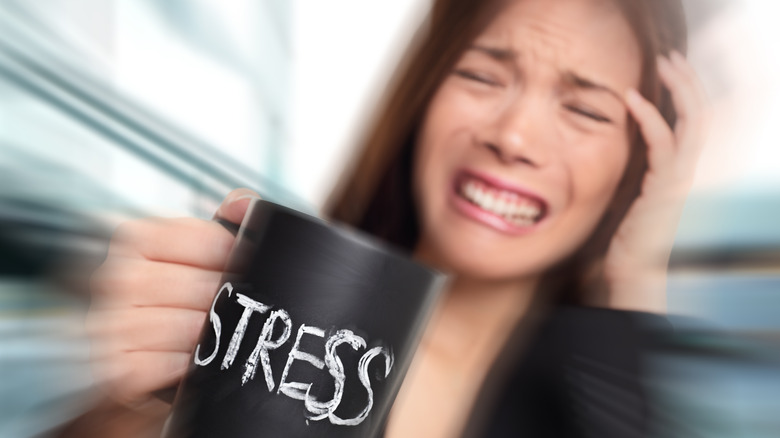 Stressed woman holding "stress" cup