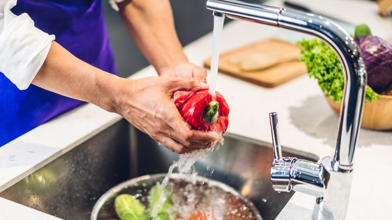 Person washing red pepper