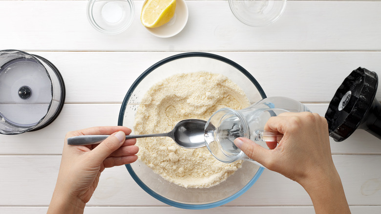 person adding water to flour