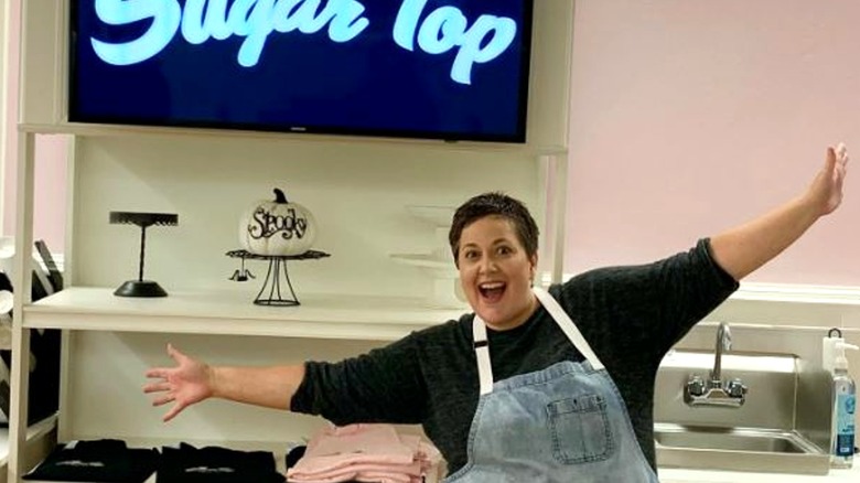 Renee Loranger holds out arms in bakery