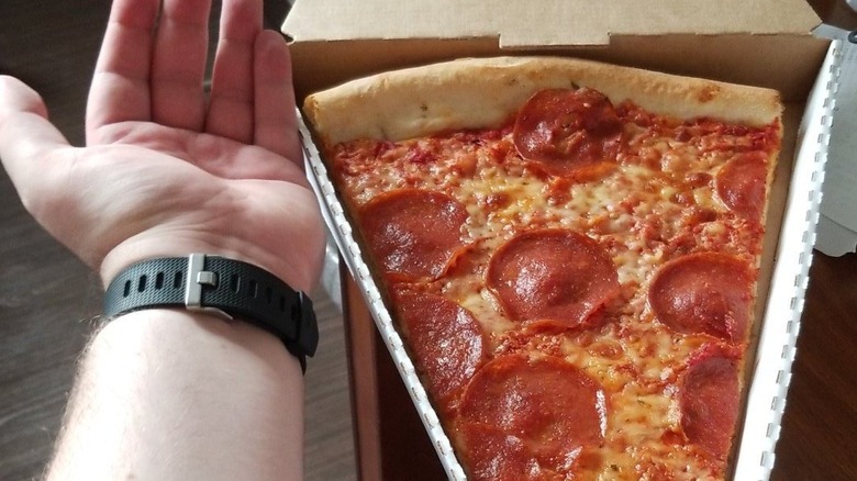 pizza slice next to hand