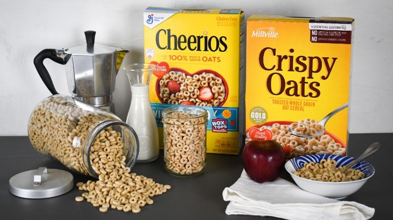 boxes of cheerios and crispy oats cereal on the breakfast table with milk, coffee, apple