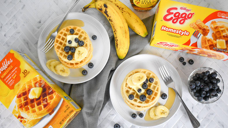 boxes of Eggo and ALDI brand frozen waffles with waffles on plates and fruit