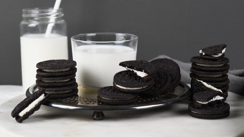 Chocolate sandwich cookies and glasses of milk on a silver plate