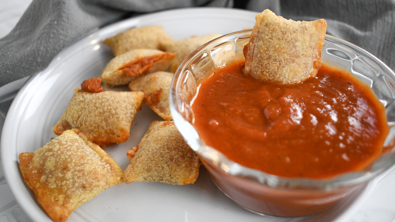 pizza rolls on a plate with a bowl of marinara dipping sauce