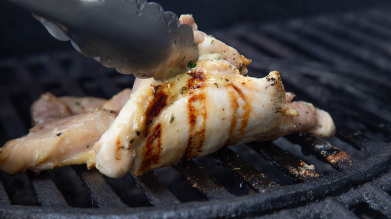 tongs lifting up grilled chicken