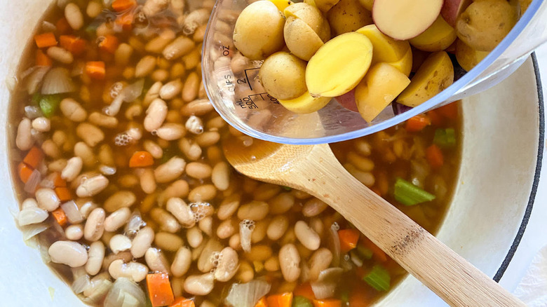 putting potatoes in bean soup