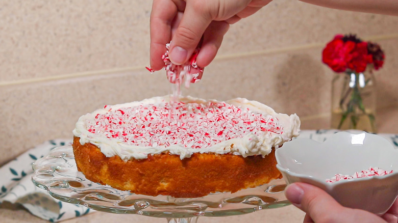 hand sprinkling peppermint on cake