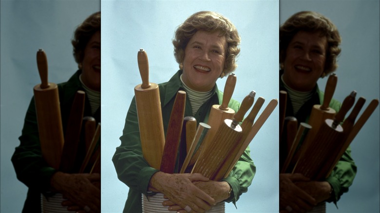 Julia Child smiling and holding rolling pins