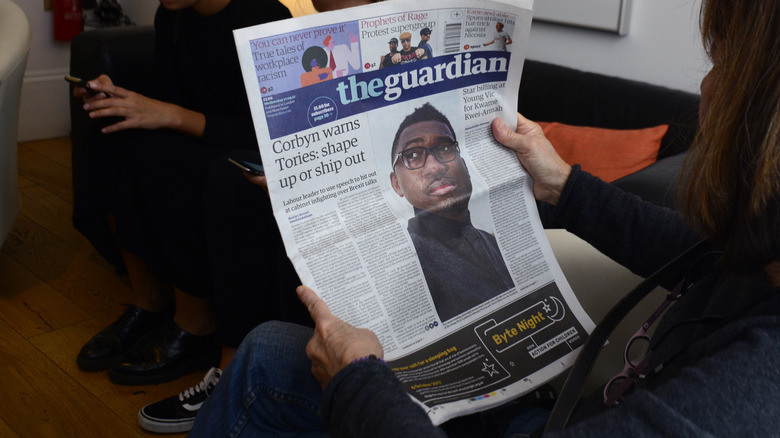 person reading The Guardian newspaper