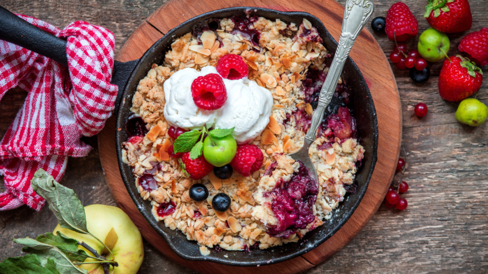 Skillet with fruit cobbler on wooden plate