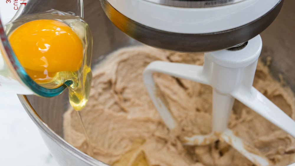 Egg being added to dry ingredients in a mixer