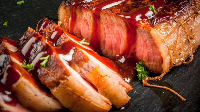 Close-up of sliced steak with brown sauce and herbs