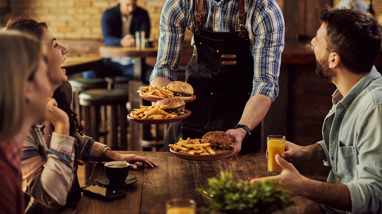 Serving handing burgers to smiling patrons