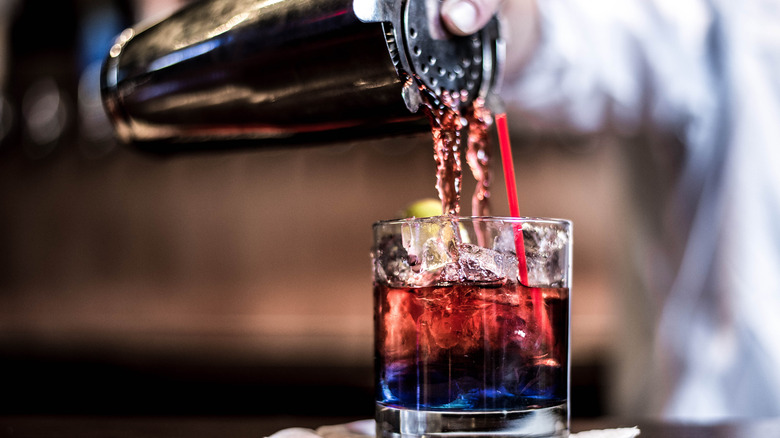 A drink being poured from a shaker into a glass 