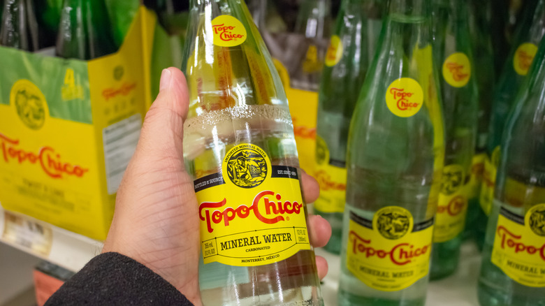 A man holding a bottle of Topo Chico 