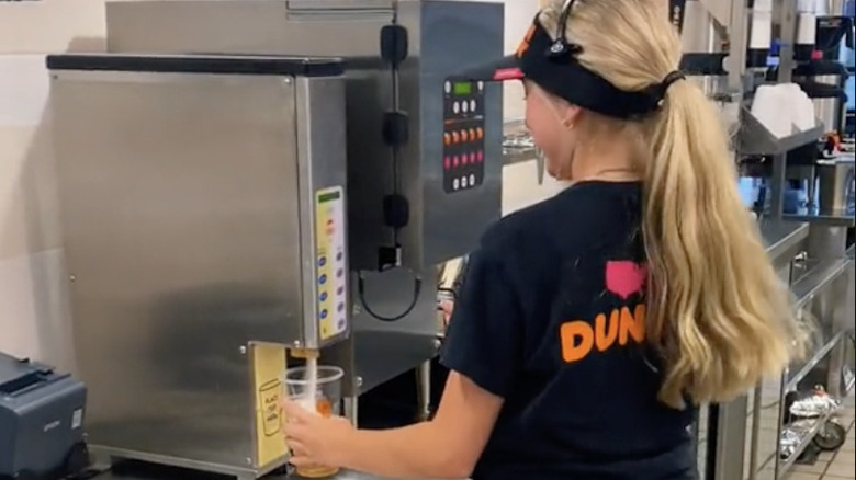 woman pouring drink from dispenser at Dunkin