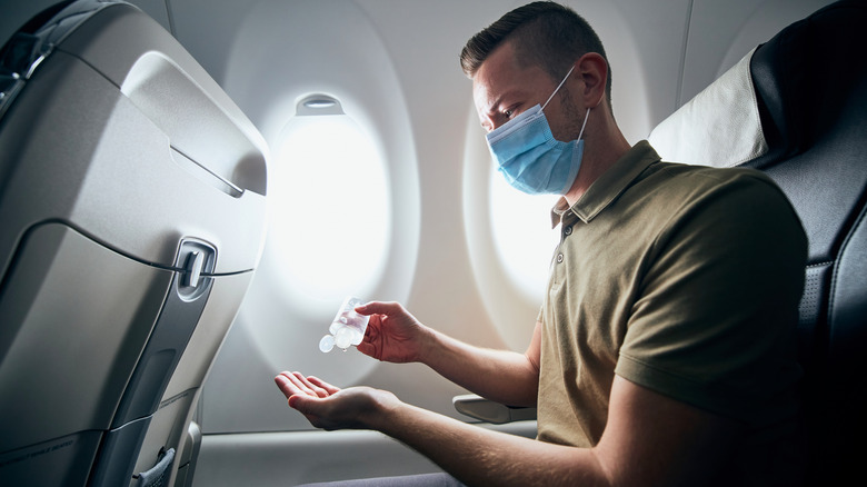 Man on plane with mask and hand sanitizer