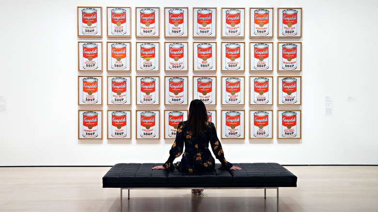 Woman sitting in front of Andy Warhol Campbell's soup display